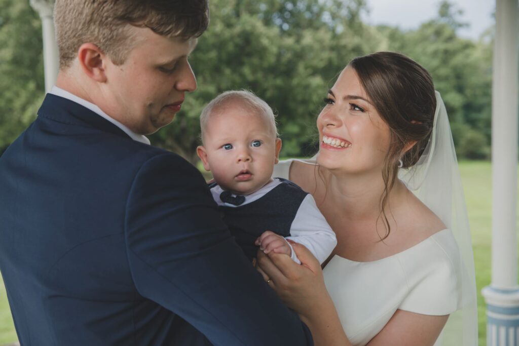 104 groom holds baby bride smiles thorganby venue grounds north yorkshire oxford wedding photography