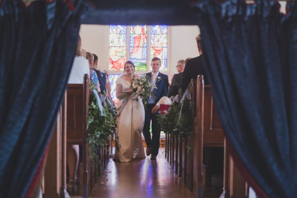 82 smiling bride groom walk up aisle thorganby north yorkshire oxford wedding photographers